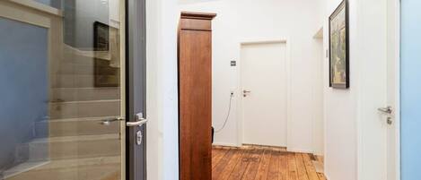 Un pasillo con piso de madera, una puerta y un armario de madera.
