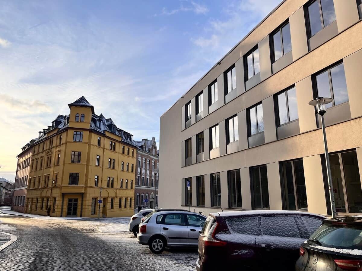A street with parked cars and a building with a modern facade.