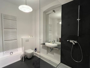 Un baño moderno con inodoro, lavamanos y ducha.