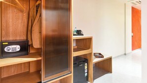 A hotel room with a wooden wardrobe, a black minibar, and a wooden desk. - Bhagwati Luxuria Hotel  (Indore)