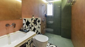 A modern bathroom with a glass-enclosed shower, a white sink, and a toilet. - Bhagwati Luxuria Hotel  (Indore)