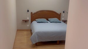 Un dormitorio con cama de madera, paredes blancas y suelo de madera.