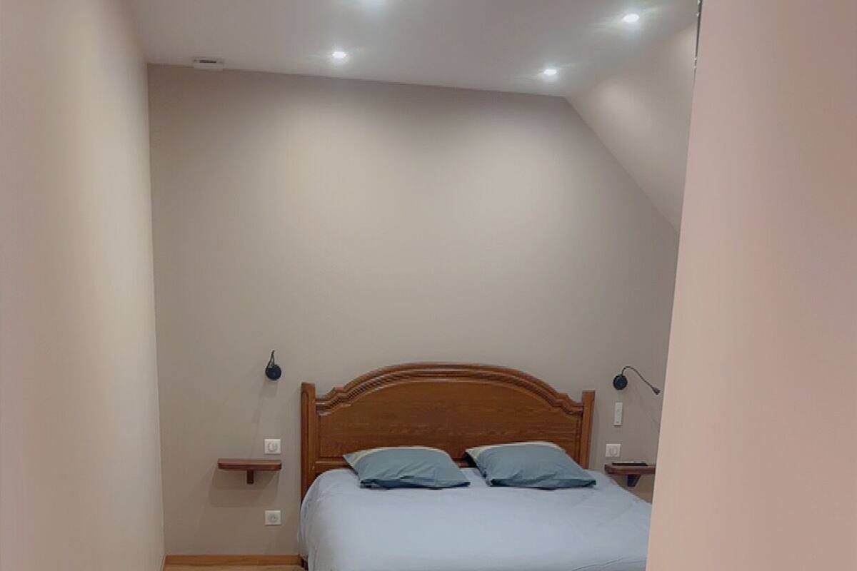 Een slaapkamer met een houten bed, witte muren en een houten vloer.