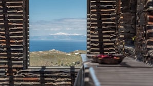 A rustic stone room with a view of a mountainous landscape and the sea. - NEVERMIND VACATIONS VILLAS (Kea)