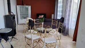 Una sala de estar con un estufa de leña negra, una vitrina de vidrio, un sofá y una mesa de comedor con sillas.