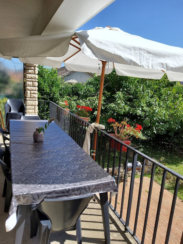 Une terrasse extérieure avec une table couverte, des chaises et des plantes en pot.