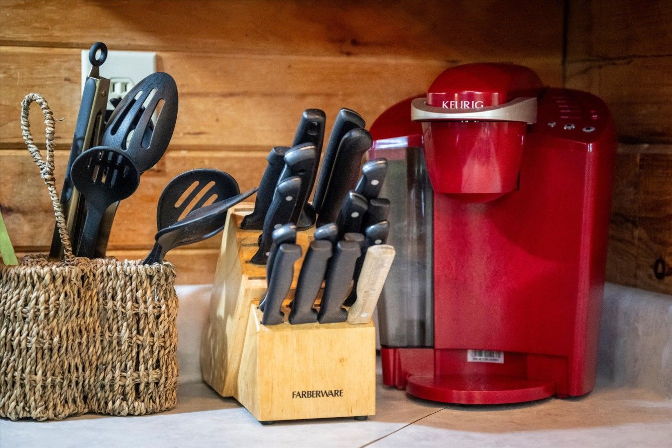 A kitchen counter with a coffee maker, a knife block, and a woven basket with utensils.