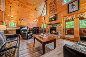A cozy cabin interior with a fireplace, leather furniture, and a stone fireplace surround. - Peaceful 2BR w/Hot Tub*Pool Table*Fireplace*Arcade (Sevierville)