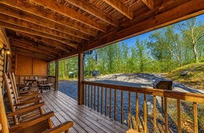 A wooden deck with benches, a covered seating area, and a view of a forested area. - Peaceful 2BR w/Hot Tub*Pool Table*Fireplace*Arcade (Sevierville)