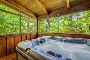 Un bain à remous sur une terrasse en bois, avec vue sur un paysage verdoyant.