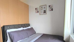 Een slaapkamer met een bed, een houten hoofdbord en drie ingelijste foto’s aan de muur.