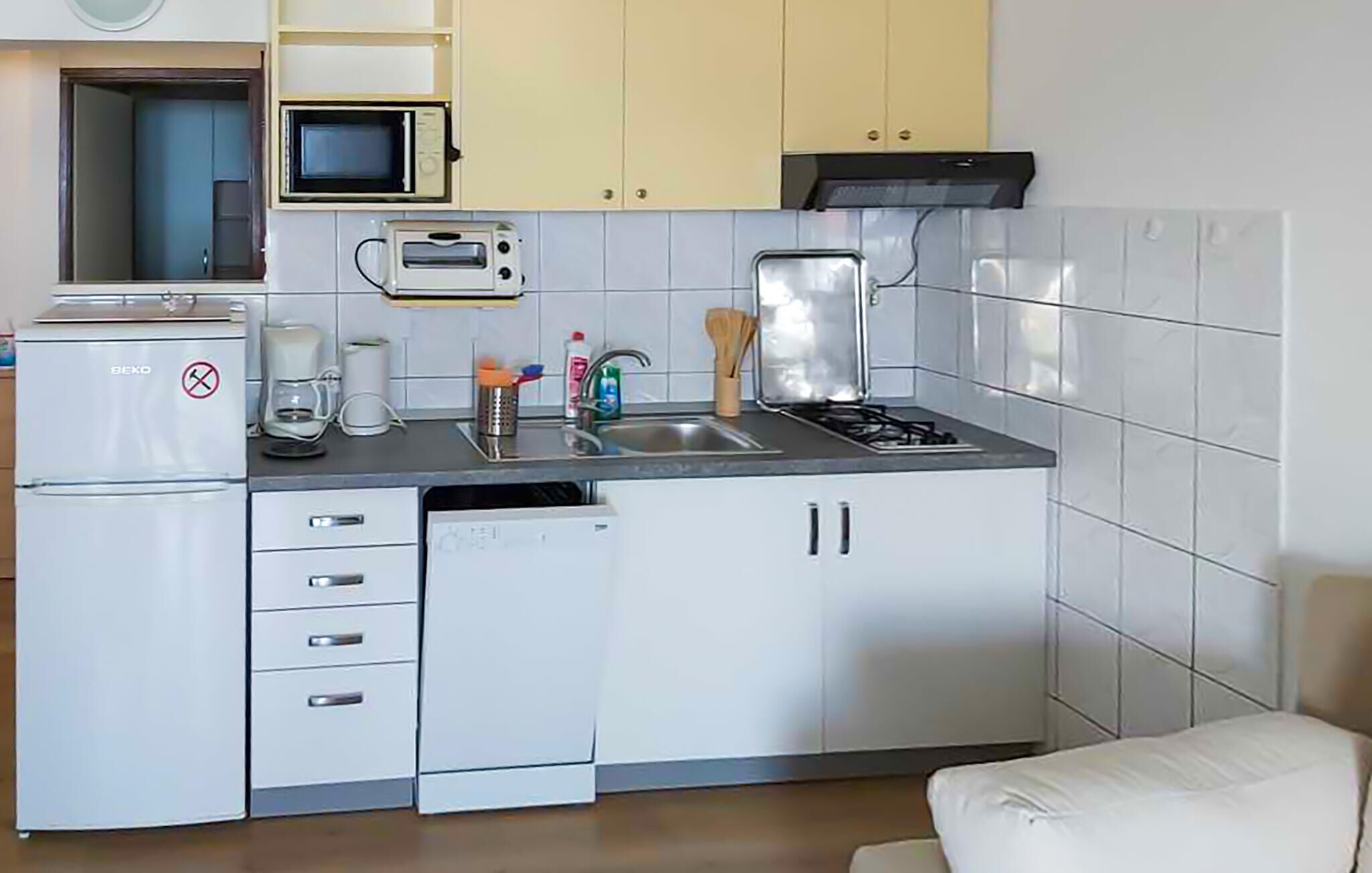 A compact kitchen with a refrigerator, microwave, toaster, sink, and stove.