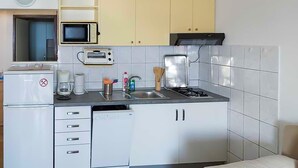 Una cucina compatta con frigorifero, microonde, tostapane, lavello e fornello.