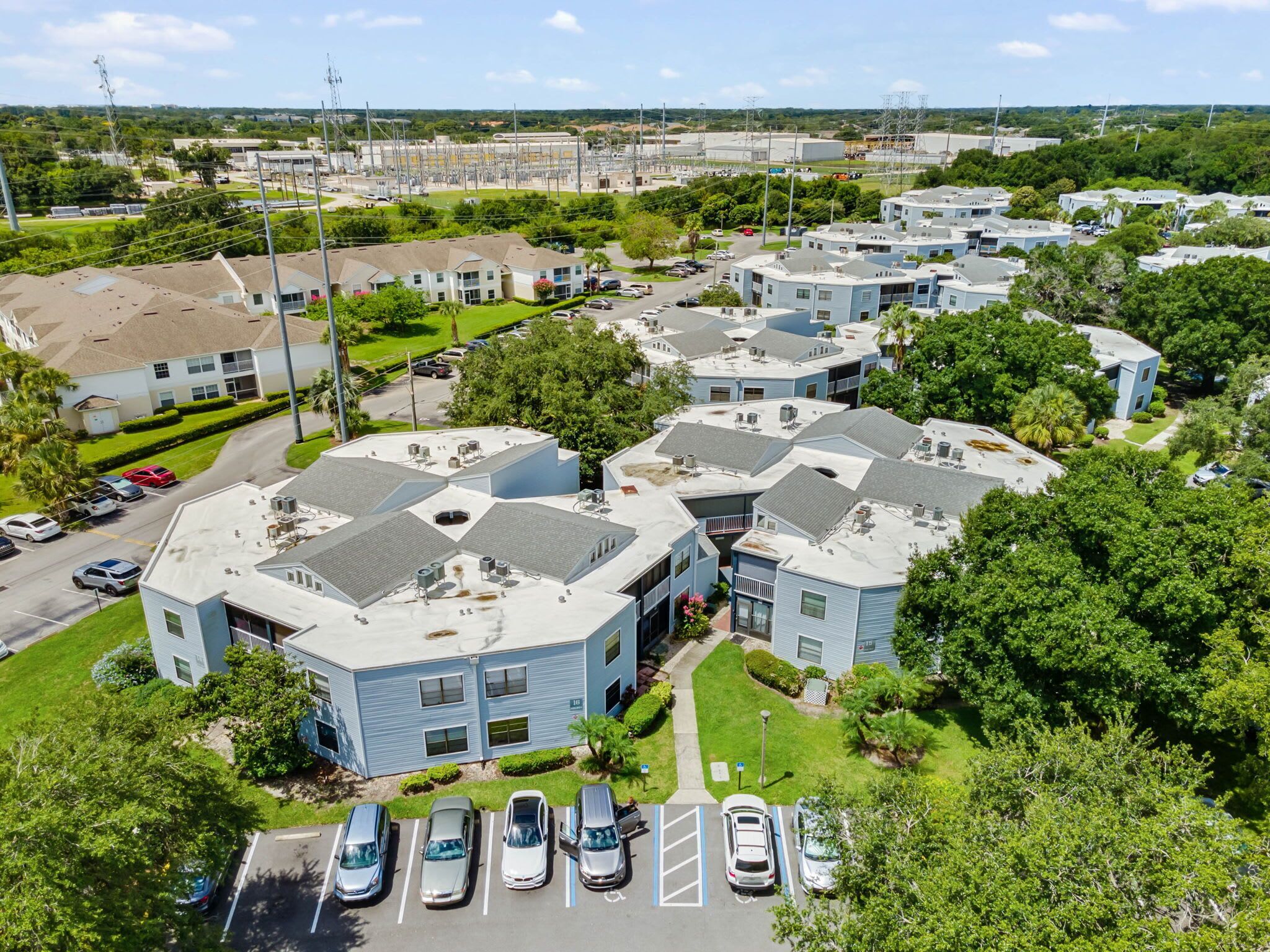 A residential area with multiple two-story buildings, each with a flat roof and a parking lot in front.