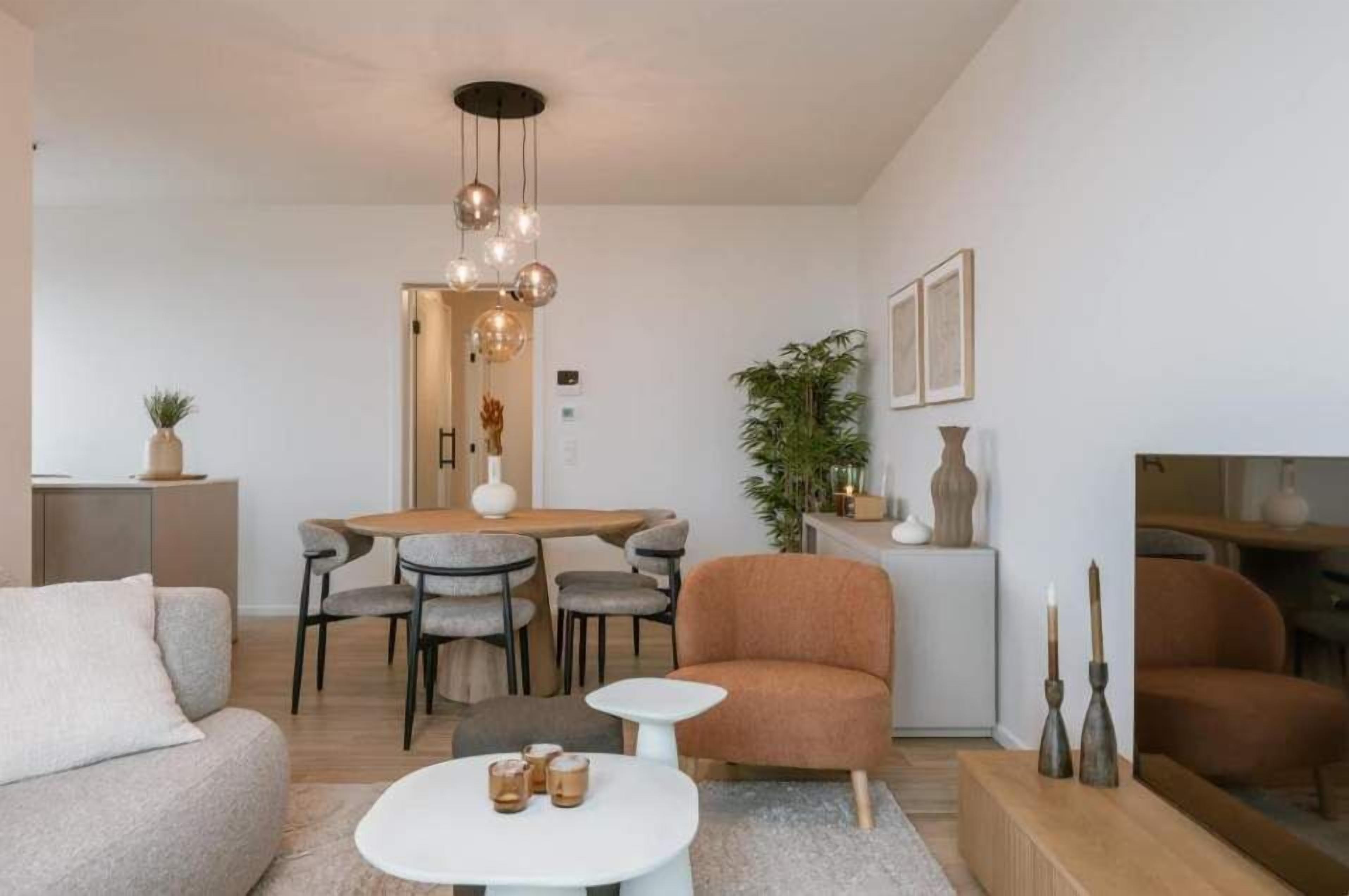 Uma sala de estar moderna com sofá, mesa de centro e área de jantar com cadeiras e mesa.