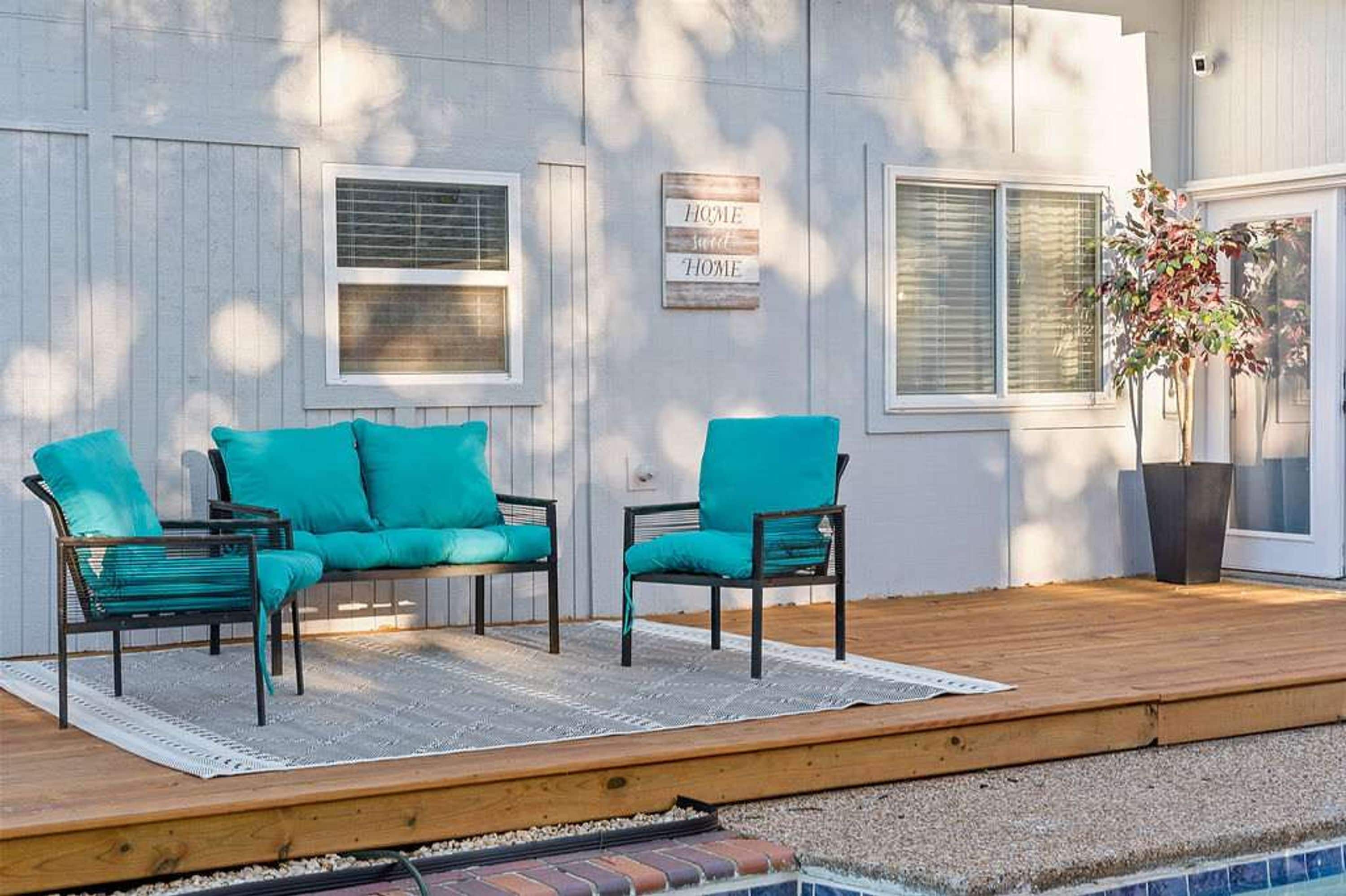 A deck with two chairs and a sofa, a sign reading 'HOME,' and a potted plant.
