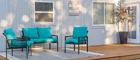 A deck with two chairs and a sofa, a sign reading 'HOME,' and a potted plant.