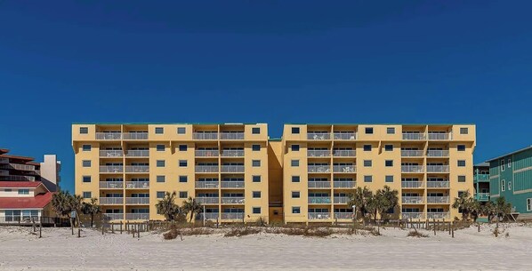 A yellow multi-story hotel with balconies, located on a sandy beach. - The Big Surf - Gulf View - Beach Pool and Dining (Gulf Shores)