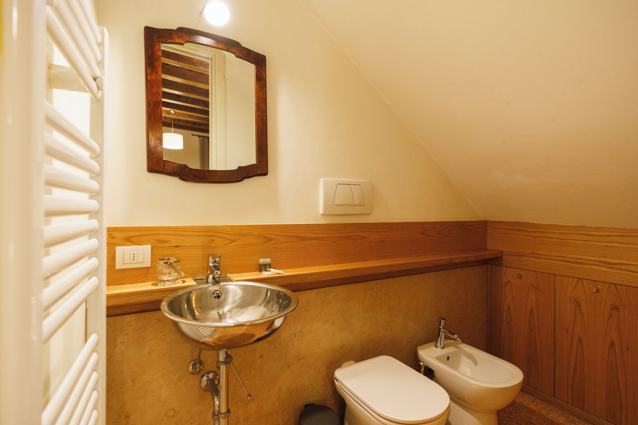 A bathroom with a wooden vanity, a sink, a toilet, and a bidet.