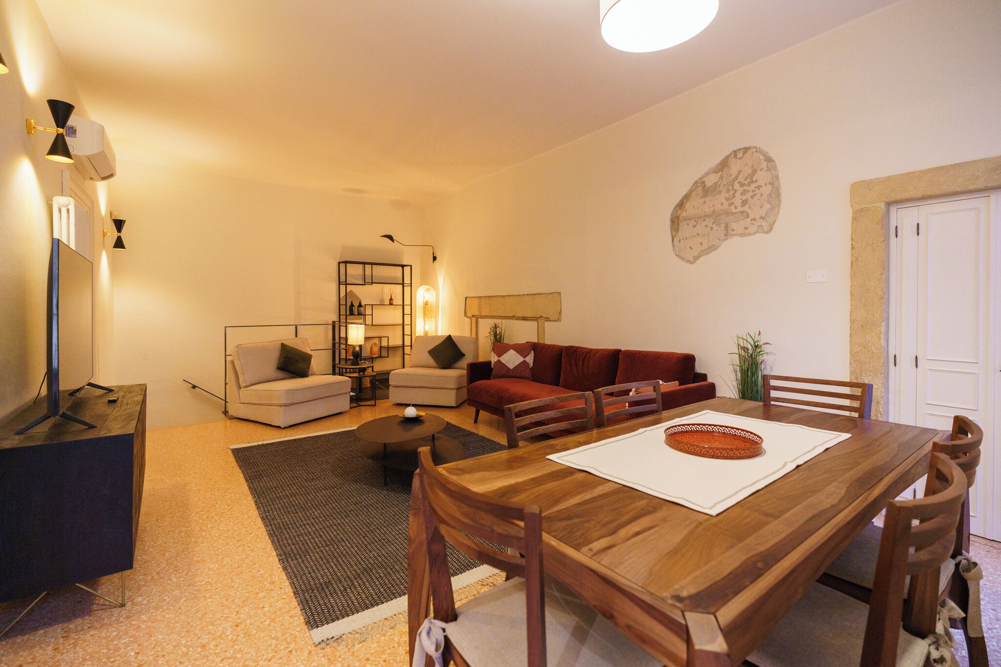 Una sala de estar con una mesa de comedor de madera, un sofá, una mesa de centro y un mueble para televisión.
