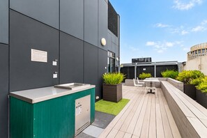 Ein moderner Außenbereich mit Grillstation, Sitzgelegenheiten und Pflanzkübeln.