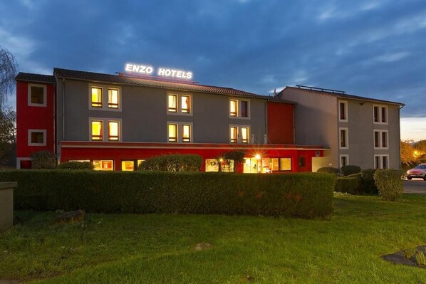 A hotel with a red and grey facade, multiple windows, and a sign reading "ENZO HOTELS". - Enzo Hotels Pont à Mousson (Pont-à-Mousson)
