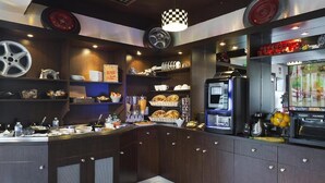 Une cuisine avec des meubles de couleur bois foncé, un luminaire suspendu à motifs à carreaux et divers appareils de cuisine.
