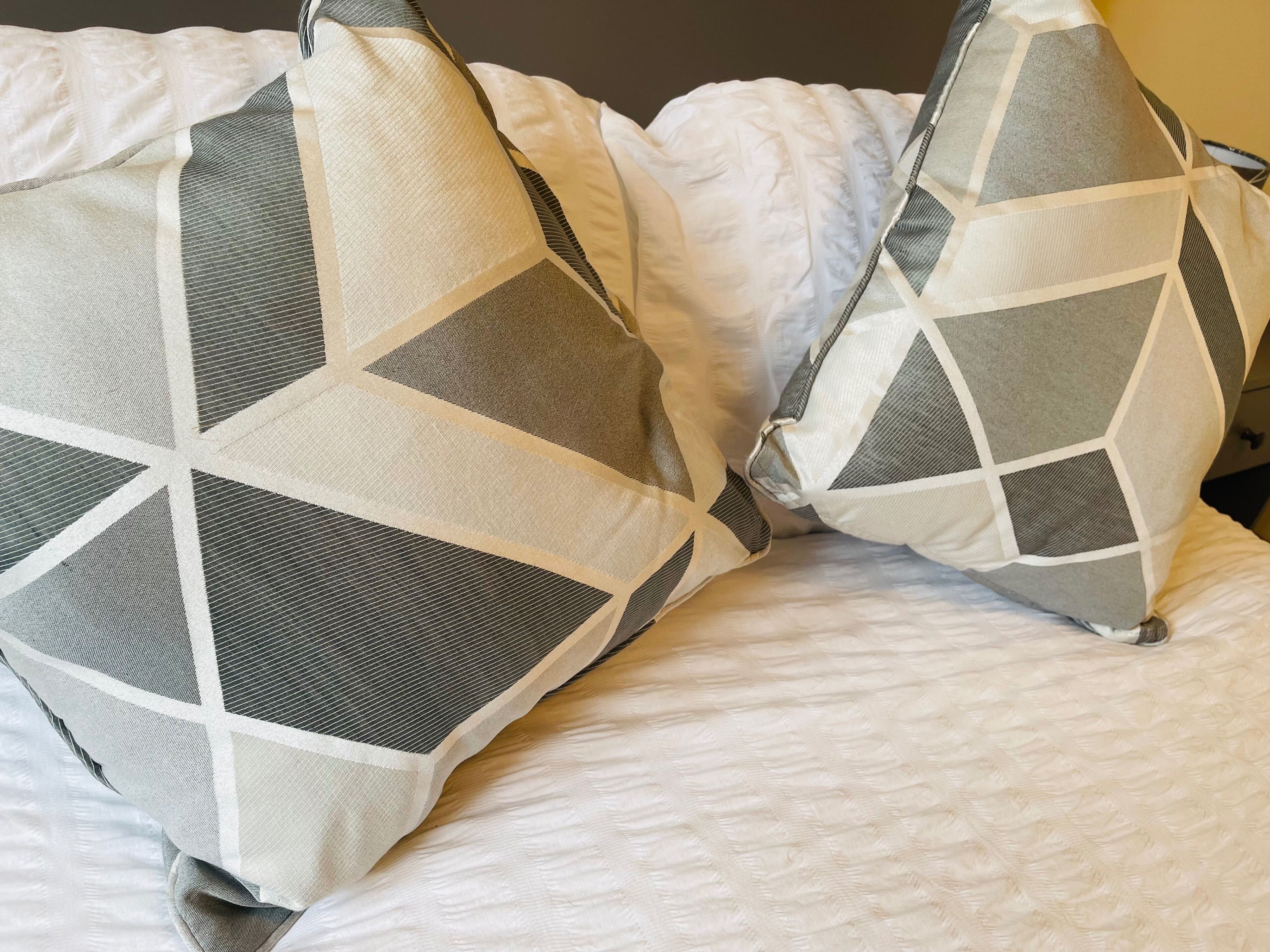Una cama con dos almohadas de estampado geométrico.