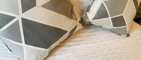 Una cama con dos almohadas de estampado geométrico.