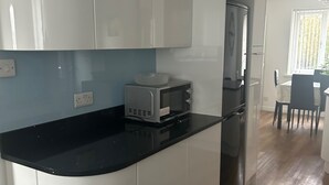 Une cuisine avec des armoires blanches, un comptoir noir, un four à micro-ondes et un réfrigérateur.