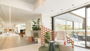 A modern lobby with a seating area, a staircase, and large windows. - Canvas Pamplona Plazaola  (Pamplona)