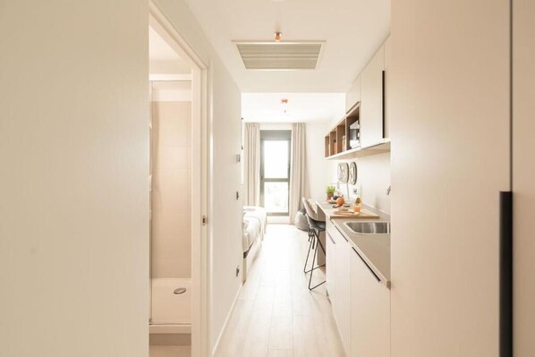 A narrow, well-lit hallway leading to a bedroom with a large window. - Canvas Pamplona Plazaola  (Pamplona)