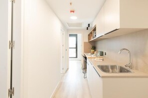 A narrow, well-lit kitchen with a sink, countertop, and cabinets. - Canvas Pamplona Plazaola  (Pamplona)