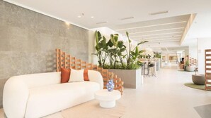 A modern interior with a white sofa, a round coffee table, and a wooden partition with plants. - Canvas Pamplona Plazaola  (Pamplona)