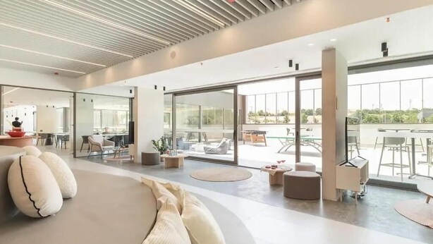 A modern interior with a curved sofa, glass doors leading to an outdoor area, and a ceiling with linear patterns. - Canvas Pamplona Plazaola  (Pamplona)