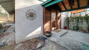 A wooden door with a small step leading up to it, a concrete pathway, and a metal fence with potted plants. - On 10 Acres! Serene Nevada City Retreat w/ Hot Tub (Nevada City)