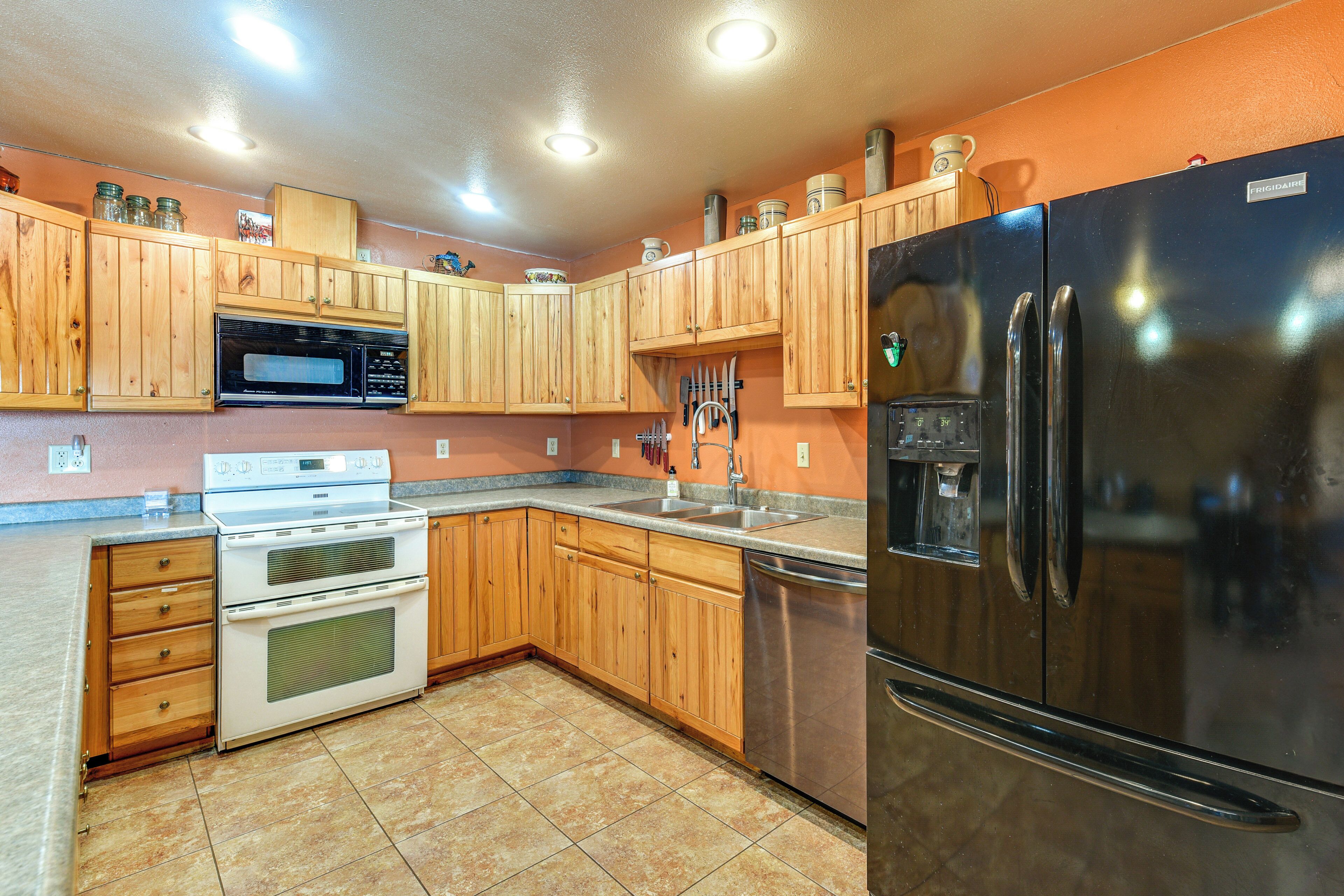 A kitchen with wooden cabinets, a stainless steel refrigerator, a microwave, and a stove.