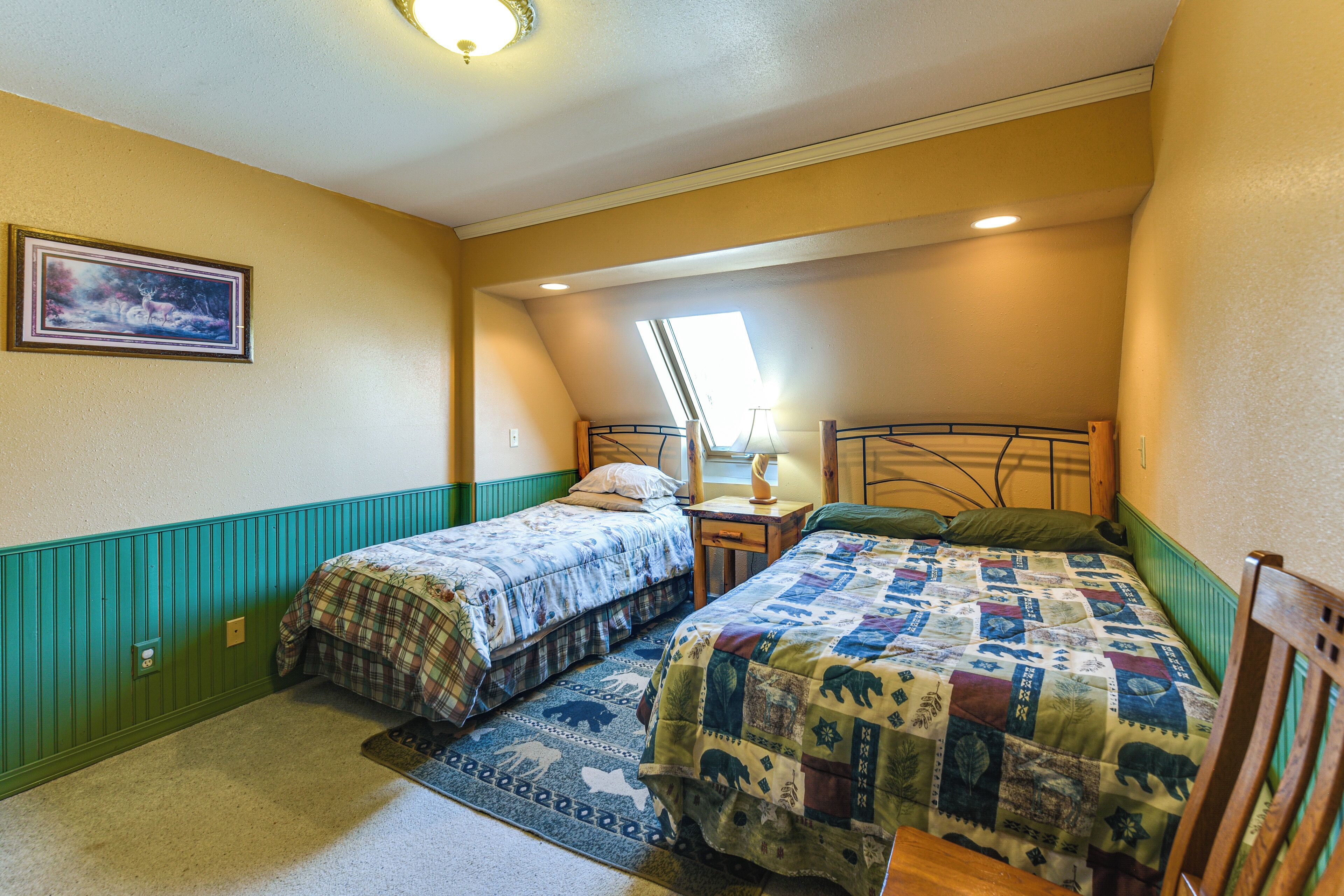 Un dormitorio con dos camas, una ventana, una mesita de noche y un cuadro colgado en la pared.