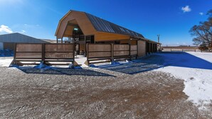 A modern building with a sloped roof and large windows, surrounded by a fenced area with snow on the ground. - Hot Tub, Fire Pit! Massive Mt Vernon Hunting Lodge (Mount Vernon)