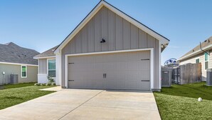 A single-story house with a garage, a front yard, and a neighboring house.