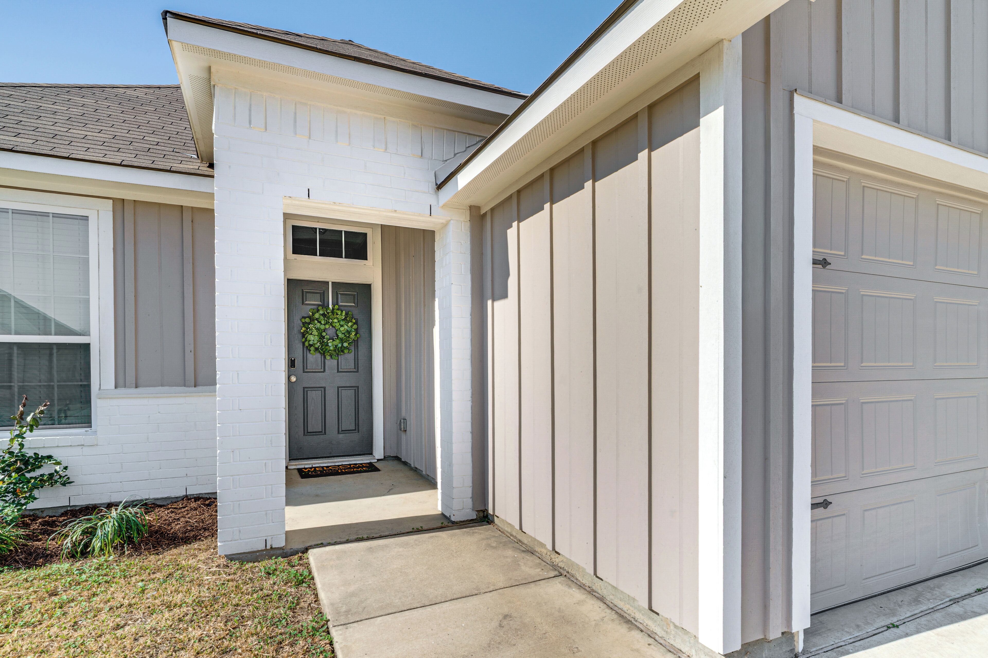 Ein Wohnhaus mit Garage, Eingangstür und einer kleinen Veranda.