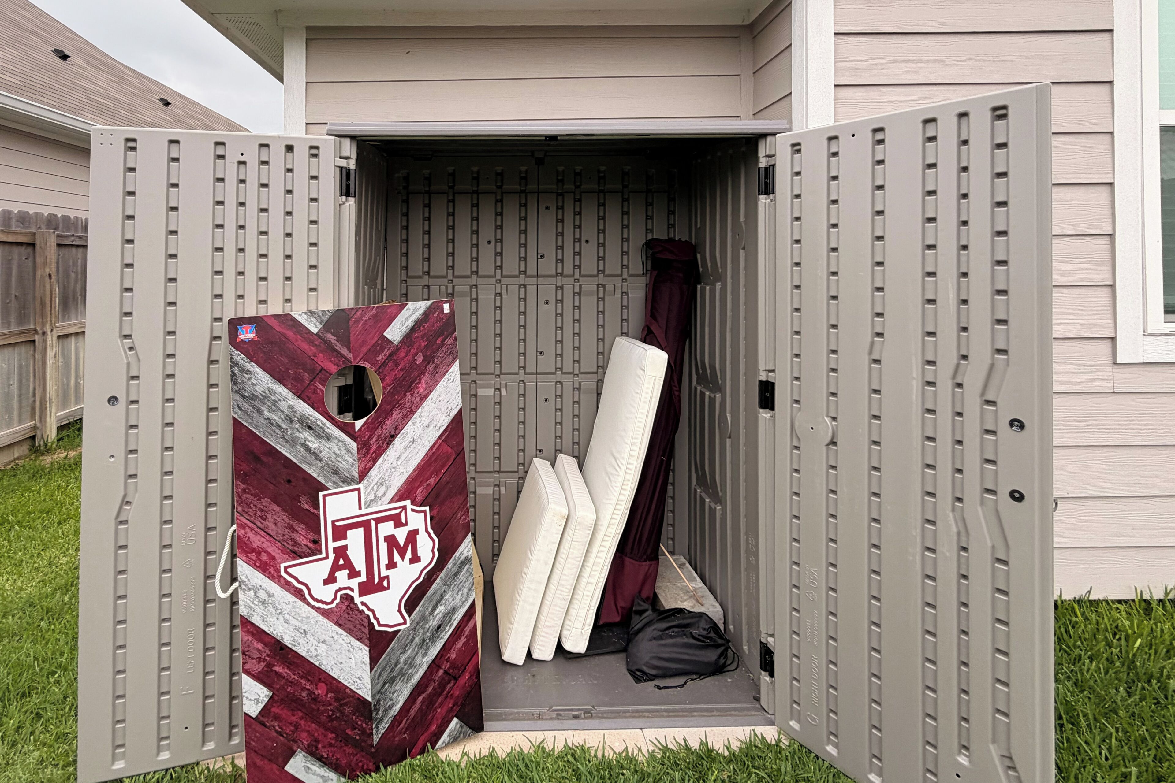 Een verplaatsbare opslagunit met een Texas A&M logo, gevuld met matrassen en een zwarte tas.