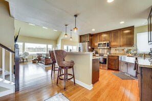 A spacious kitchen with wooden cabinets, a central island, and pendant lighting.