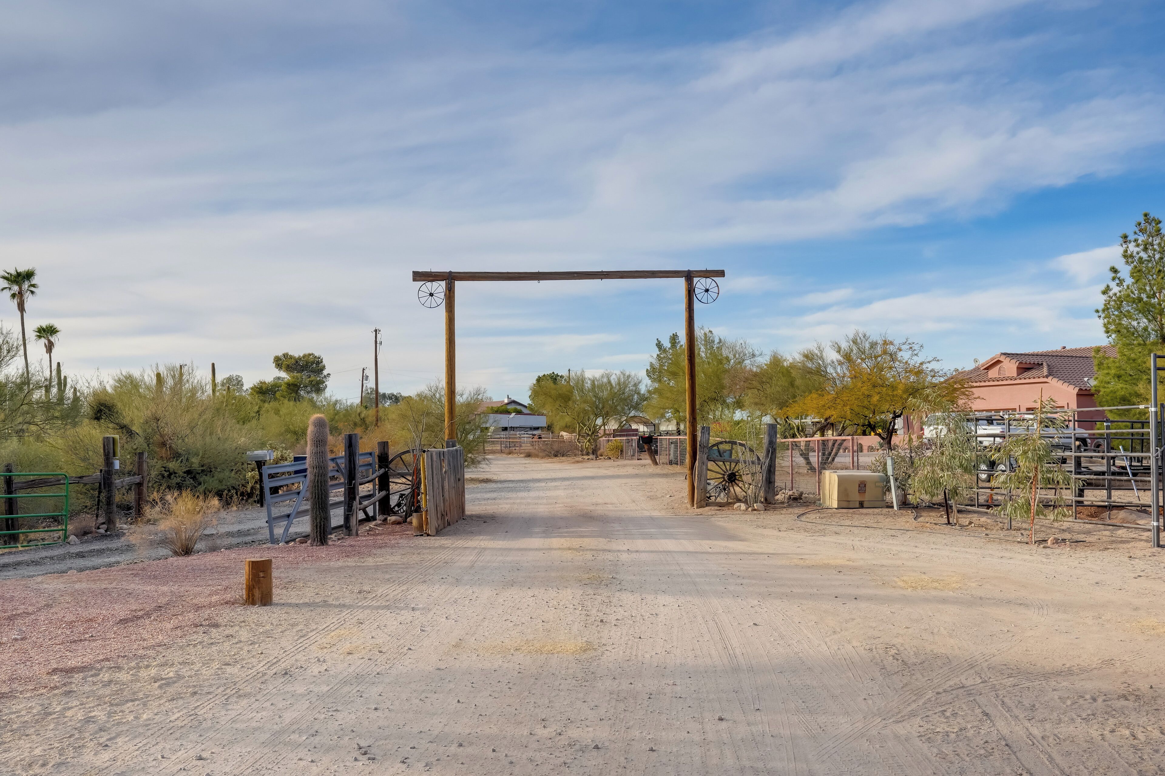 A dirt road leading to a gated entrance with a wooden archway.
