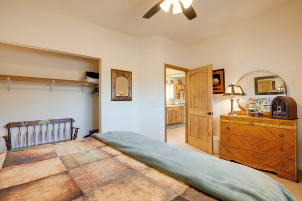 A bedroom with a bed, wooden dresser, and a mirror.