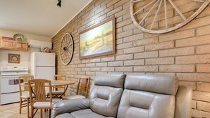 A cozy kitchen with a leather sofa, wooden chairs, and a brick wall. - Horse Ranch Hideaway! Wickenburg Equestrian Casita (Wickenburg)