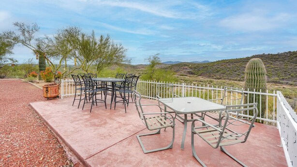 An outdoor patio with a table and chairs, surrounded by a white fence, overlooking a desert landscape with cacti and sparse vegetation. - Horse Ranch Hideaway! Wickenburg Equestrian Casita (Wickenburg)