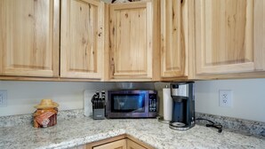A kitchen with wooden cabinets, a microwave, a coffee maker, and a decorative item on the counter. - Horse Ranch Hideaway! Wickenburg Equestrian Casita (Wickenburg)