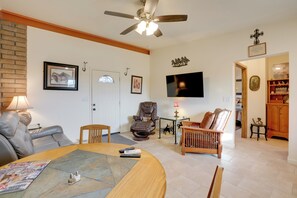 A living room with a sofa, a recliner, a wooden coffee table, and a television mounted on the wall.