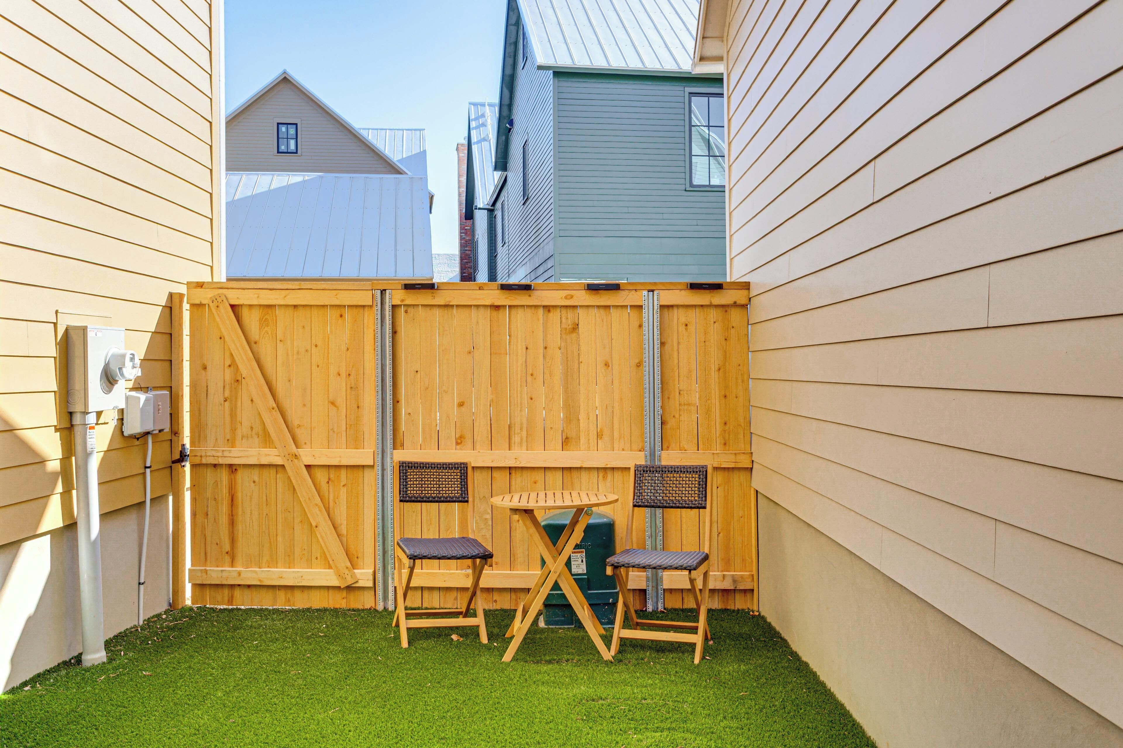 A fenced backyard with a small table and two chairs.